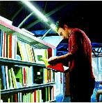 books- hyperrealism painting by artist Gerard Boersma showing man in front of bookshelf reading in public library