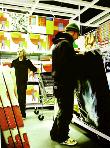 ikea- hyperrealism acrylic painting by artist painter Gerard Boersma showing man going through abstract paintings in ikea store gallery, woman with shopping cart in back